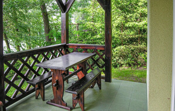 A wooden gazebo with a bench and table, surrounded by lush greenery.