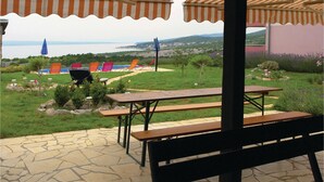 An outdoor patio area with picnic tables and chairs, a barbecue grill, and a view of the sea. - Awesome apartment in Klenovica with WiFi (Klenovica)