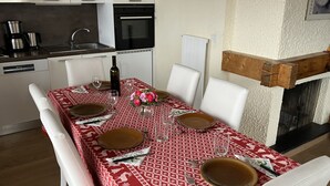 Ein Essbereich mit rotem, gemustertem Tischlein, weißen Stühlen und einem Kamin.