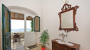A room with a wooden dresser, a mirror, a potted plant, and a view through an open door. - Awesome home in Trsteno with sauna (Trsteno)