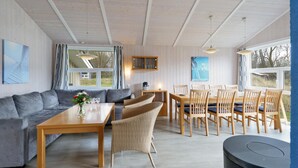A cozy room with a sofa, dining table, wicker chairs, and a small round table.