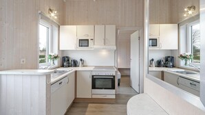 A compact kitchen with white cabinetry, a microwave, a coffee maker, and a stove.