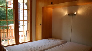 Une chambre avec deux lits, des murs en bois et une grande fenêtre donnant sur l’extérieur.