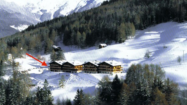 Une station de montagne enneigée, avec une rangée de chalets en bois.