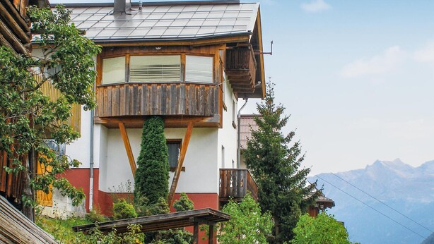 A chalet with a wooden balcony, a chimney, and a mountain backdrop. - Ferienhaus in ruhiger Lage (Kappl)
