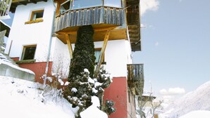 A multi-story building with a wooden balcony and a red wall. - Ferienhaus in ruhiger Lage (Kappl)