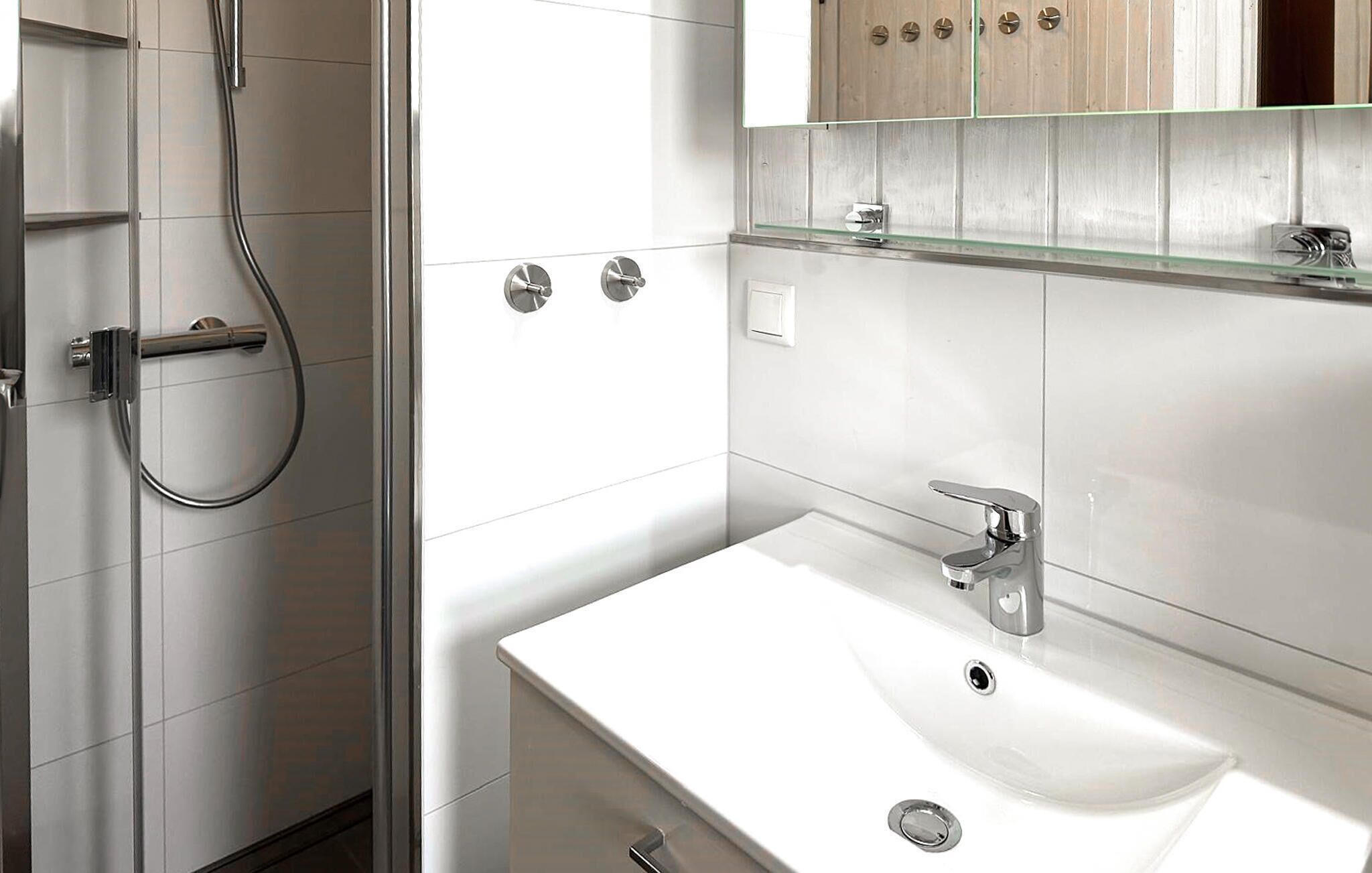 A modern bathroom with a white sink, chrome fixtures, and a glass shower enclosure.