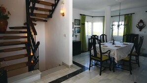 A dining area with a table set for four, surrounded by chairs, a staircase, and a chandelier. - Beautiful apartment in Calahonda (Calahonda)