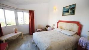 A bedroom with a bed, a chair, a small table, a lamp, and a painting on the wall. - Beautiful apartment in Calahonda (Calahonda)