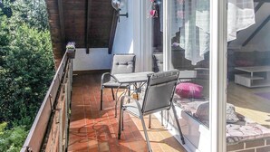 Een balkon met een tafel en stoelen, een hangende lantaarn en uitzicht op de tuin.