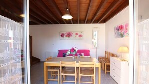 Un rincón comedor acogedor con una mesa y sillas de madera, un sofá rosa y un aparador blanco con una lámpara.