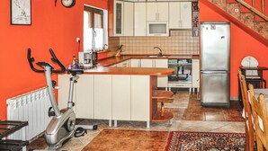 Een compacte keuken met een centraal eiland, een inbouwfornuis, een koelkast, en een eethoek met een stoel.