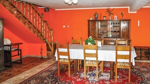 Een eetruimte met een houten tafel en stoelen, een rood tapijt en een trap met houten leuningen.