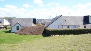 Una fila di case moderne con tetti spioventi e un'area verde con un mucchio di fieno.