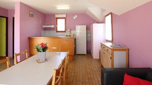 Una cucina compatta con zona pranzo, frigorifero, forno a microonde e un piccolo mobiletto.