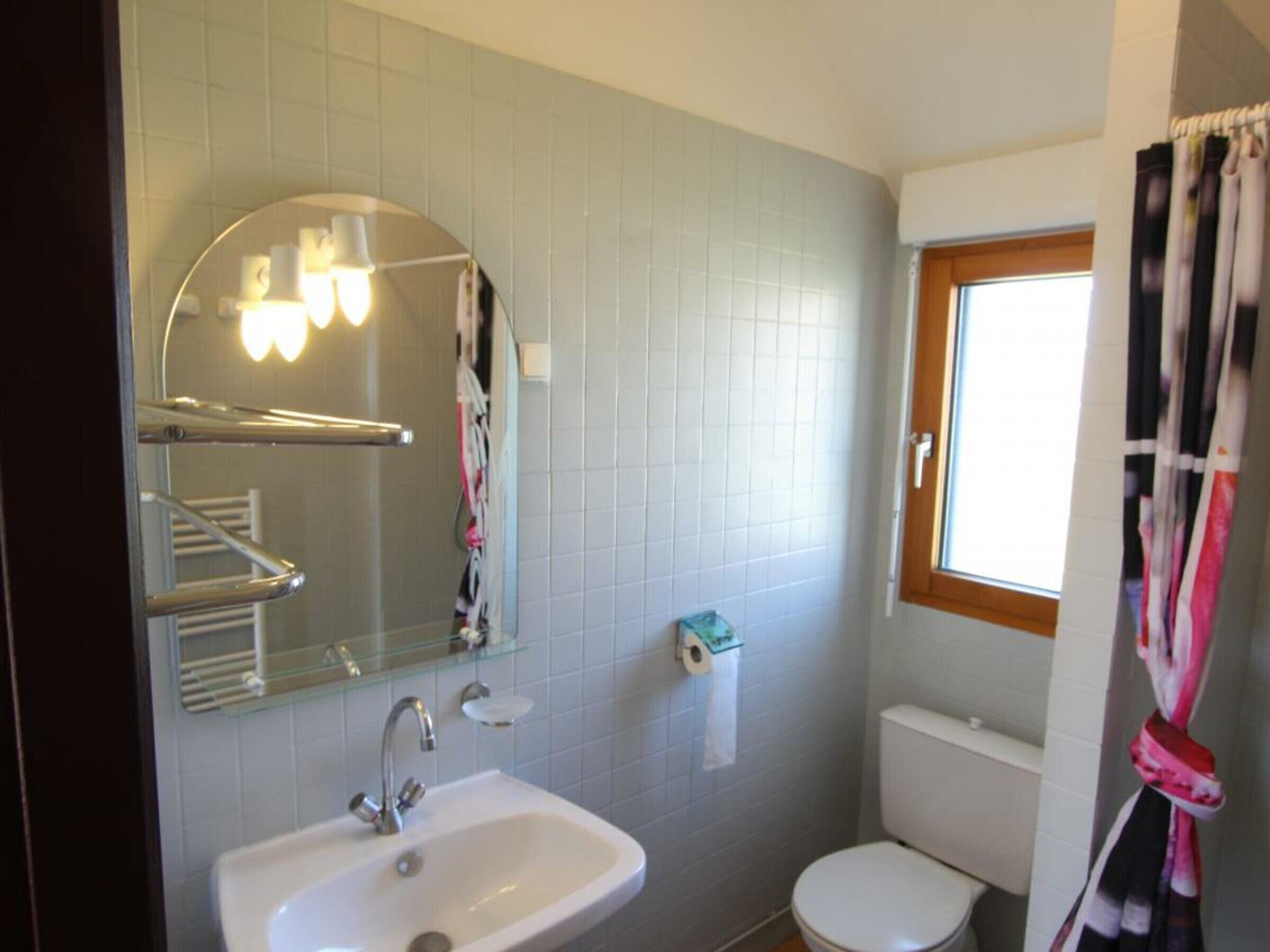 A bathroom with a white sink, a mirror, and a toilet.