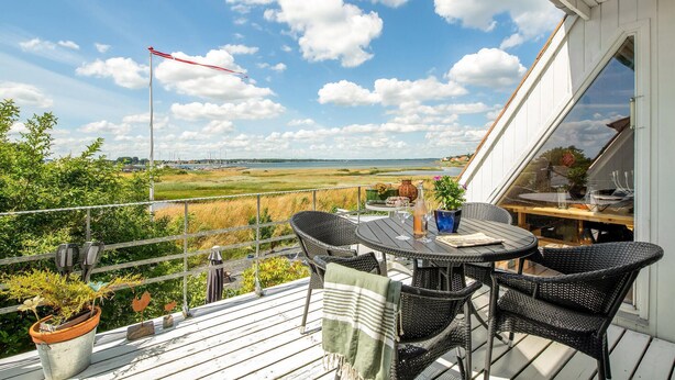 A balcony with wicker furniture, a table, and potted plants. - Amazing home in Haderslev (Haderslev)
