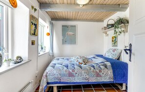 Um quarto com cama, janela, ventilador de teto e parede com pôster.