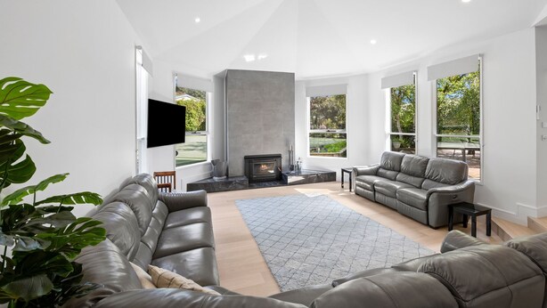 A modern living room with a fireplace, leather sofas, a flat-screen TV, and large windows offering a view of the outdoors. - THE LODGE - TENNIS,LGE SPA,WOOD FIRE, (Anglesea)
