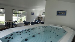 A room with a large indoor hot tub, a table with chairs, and a bookshelf. - THE LODGE - TENNIS,LGE SPA,WOOD FIRE, (Anglesea)