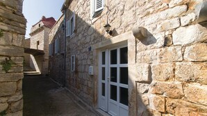 Un carreró de pedra estret amb un edifici que té una porta blanca i persianes.