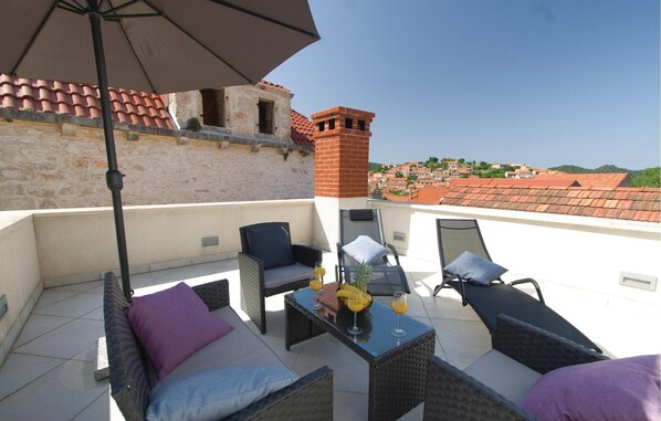 Relax on the rooftop terrace with a view of the surrounding architecture, featuring wicker furniture and a glass table.