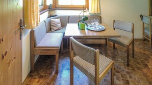 A cozy dining area with a wooden table, two chairs, a bench, and a potted plant. - Ferienwohnung in Obernberg (Obernberg)