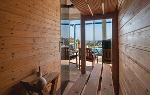 A wooden interior with a glass door leading to an outdoor seating area with a pool view. - Stunning home in Stomorska with sauna (Stomorska)