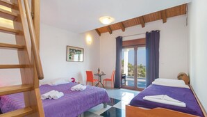 A hotel room with two beds, a wooden ladder, a small table with chairs, and a view of the outdoors.
