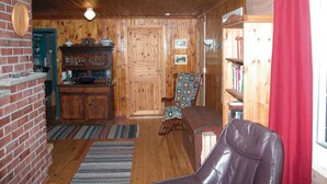 A cozy room with a brick fireplace, wooden walls, a rocking chair, and a leather chair. - Beautiful home in Tonstad with ethernet internet (Tonstad)