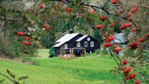 A black house with a chimney, a swing set, and a small shed in a grassy field with trees in the background. - Beautiful home in Tonstad with ethernet internet (Tonstad)