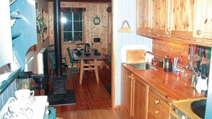 A rustic kitchen with wooden cabinets, a stove, and a dining area with chairs and a table. - Beautiful home in Tonstad with ethernet internet (Tonstad)
