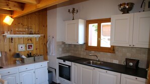 Eine Küche mit weißen Schränken, einer schwarzen Arbeitsplatte, einem Spülbecken und einem Fenster mit Blick nach draußen.