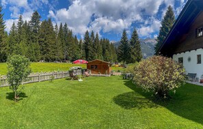 Une cabane en bois dotée d’un porche, entourée d’une clôture en bois, d’une pelouse et avec une chaîne de montagnes en toile de fond.