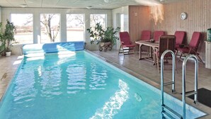 Una piscina al coperto con acqua cristallina, una scaletta e un’area relax con sedie e un tavolo.