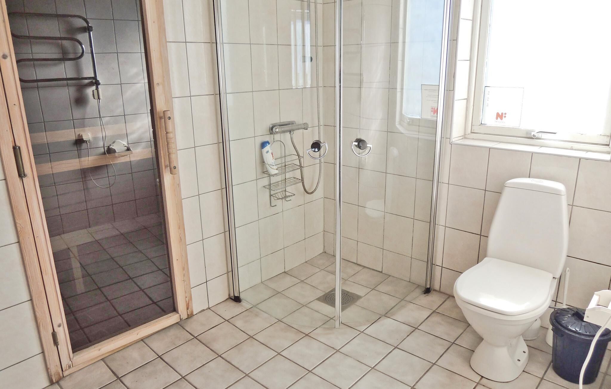 A bathroom with a glass-enclosed shower, a white toilet, and a tiled floor.