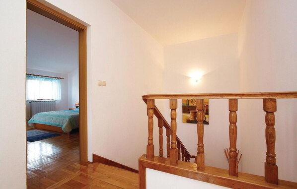 A wooden staircase with a handrail, leading to a bedroom with a bed and a window with curtains. - Cozy home in Pula with private swimming pool, can be inside or outside (Pula)
