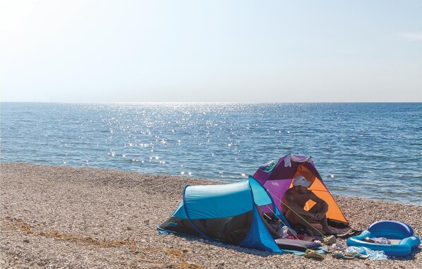 A beach with a tent and a blue inflatable ring. - Stunning home in Pula (Pula)
