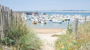 Een jachthaven met tal van boten afgemeerd, omringd door een zandstrand en een houten hek.