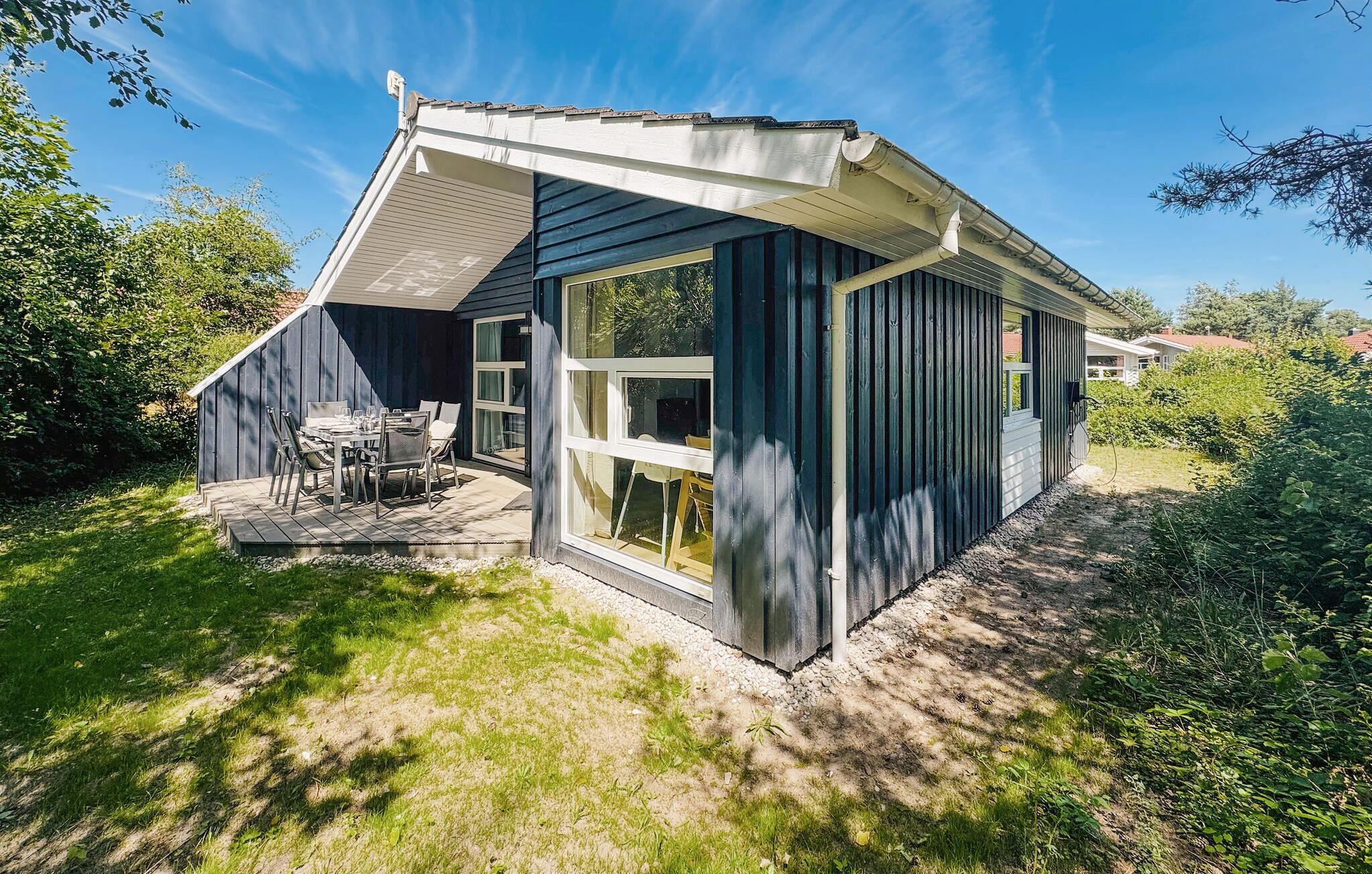 A modern house with a large deck, a dining area, and a garage.