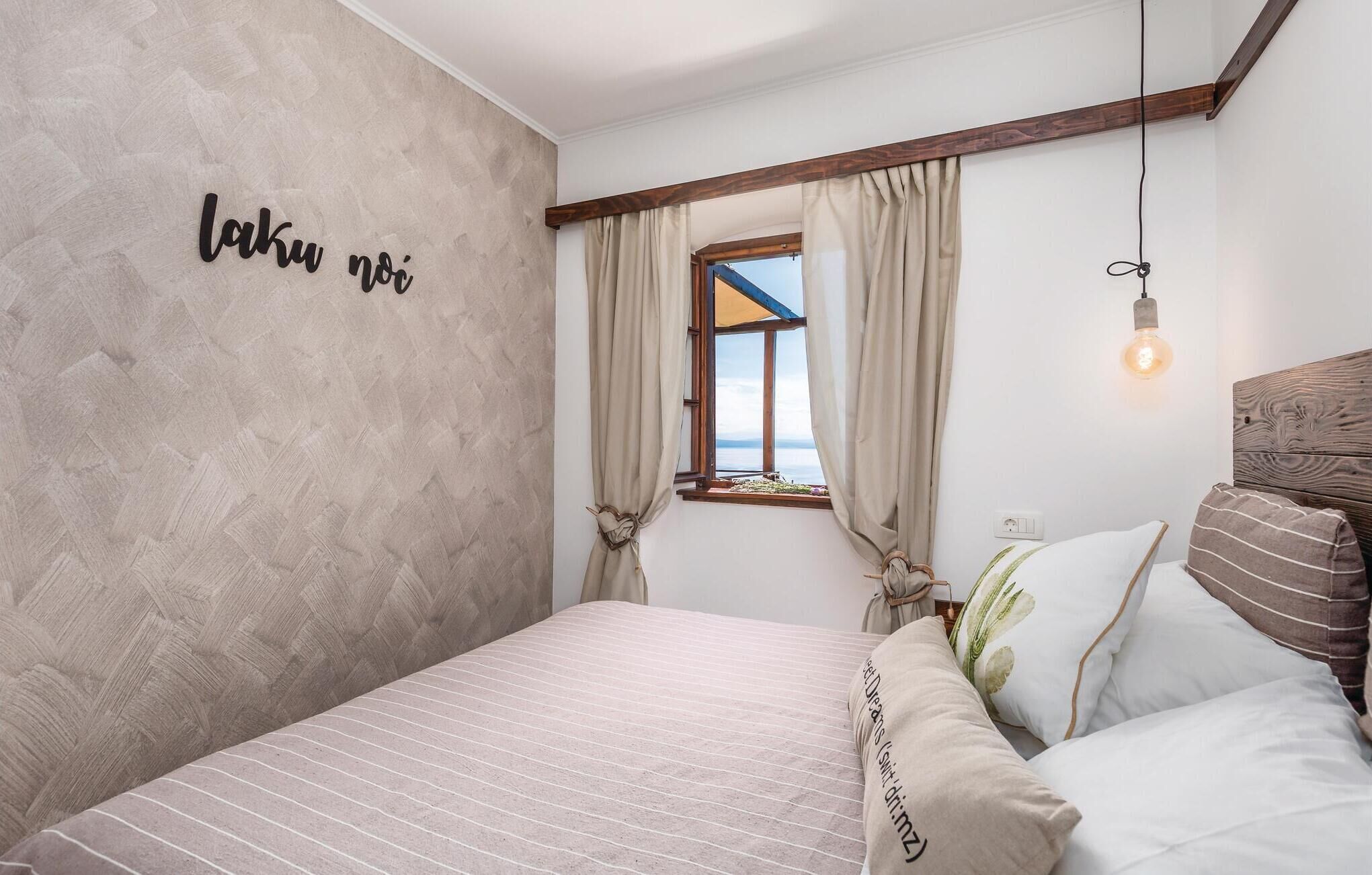 Ein Schlafzimmer mit Bett, einem Vorhangfenster, einer Wand mit Text und einer hängenden Glühbirne.