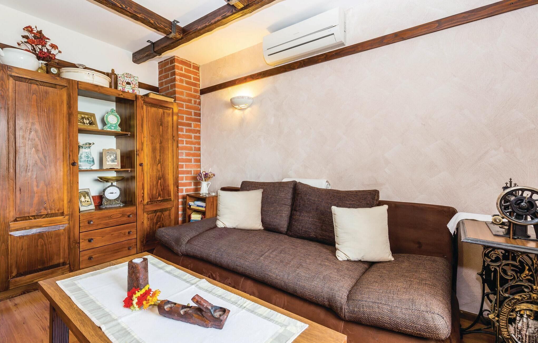 Een gezellige woonkamer met een bruine bank, een houten kast en een kleine tafel met bloemen.