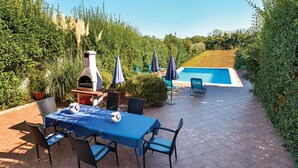 An outdoor patio with a table and chairs, a barbecue grill, and a swimming pool. - Stunning home in Pula (Pula)