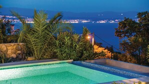 Una piscina infinita con vista a un paisaje urbano al atardecer.
