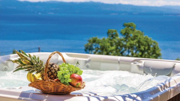 Tinaco con una cesta de mimbre que contiene frutas y vista al mar.