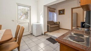 A compact kitchen with a dining area, a refrigerator, a sink, and a small table with chairs. - Nice home in Klenovica with WiFi (Klenovica)
