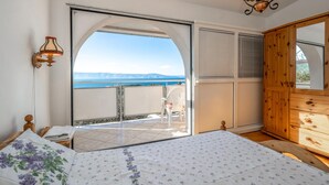 A bedroom with a bed, a wooden wardrobe, a nightstand, a lamp, and a view of the sea through an open door. - Nice home in Klenovica with WiFi (Klenovica)