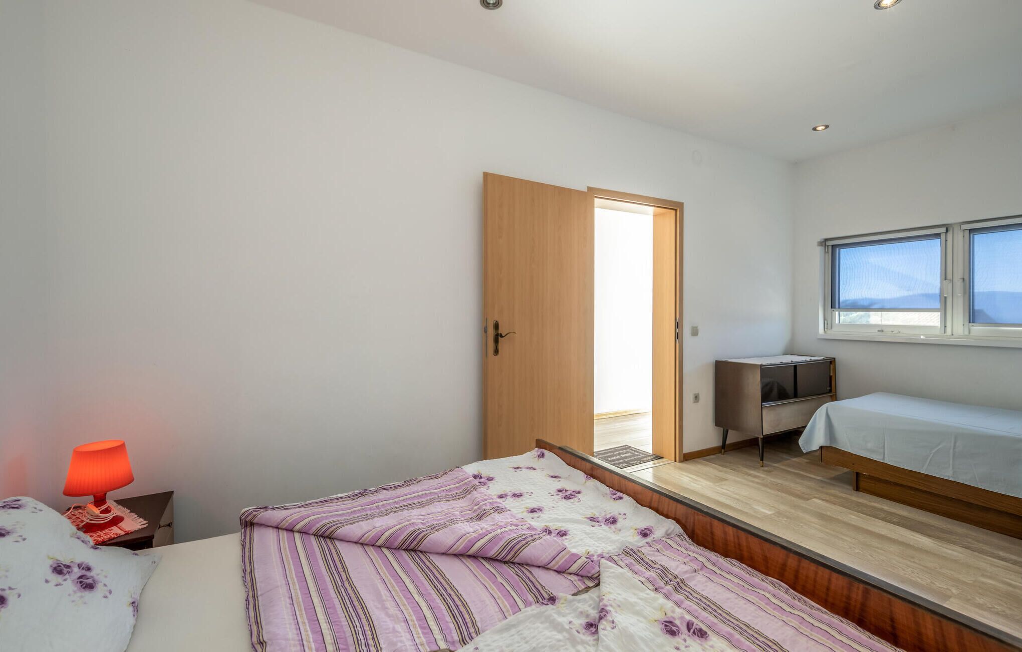 A bedroom with a bed, a desk, and a window.