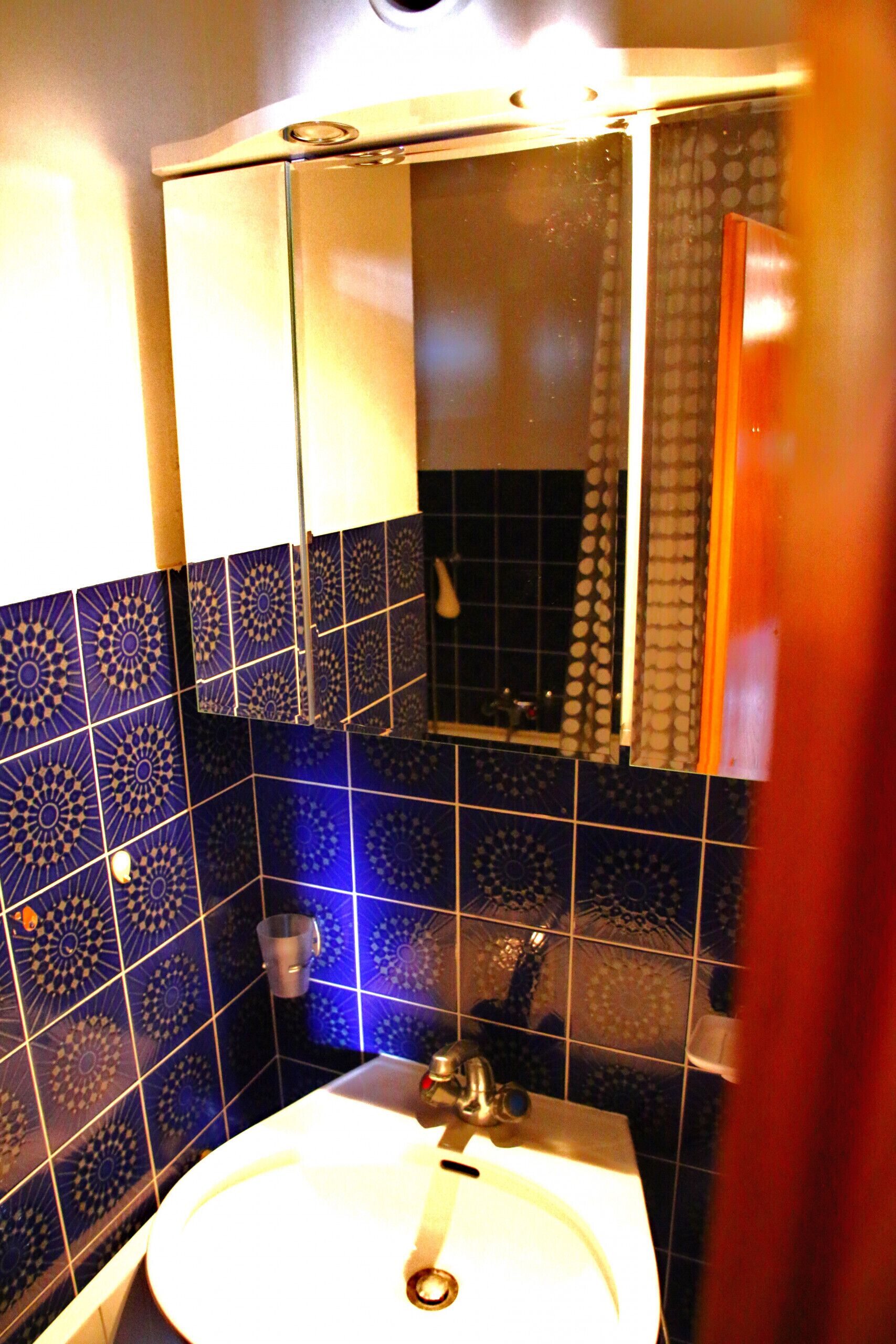 Ein Badezimmer mit Waschbecken, Spiegel und gemusterten Fliesen.