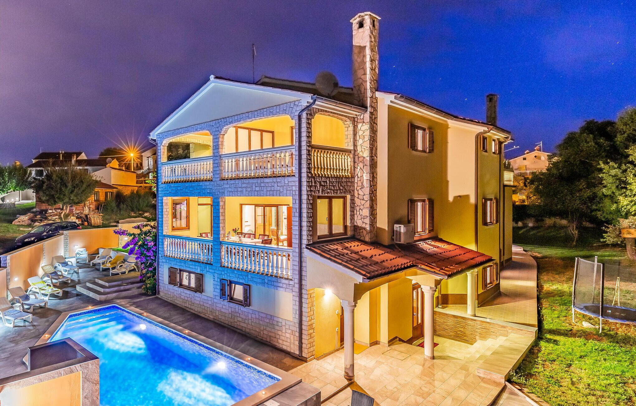 A two-story house with a swimming pool, a covered patio, and a garden.